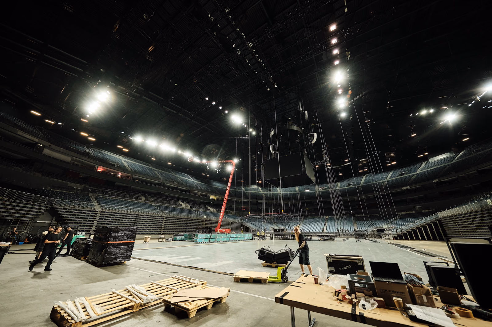 Die leere LANXESS arena am Aufbautag, Bühnenteile und Paletten stehen auf dem Hallenboden.