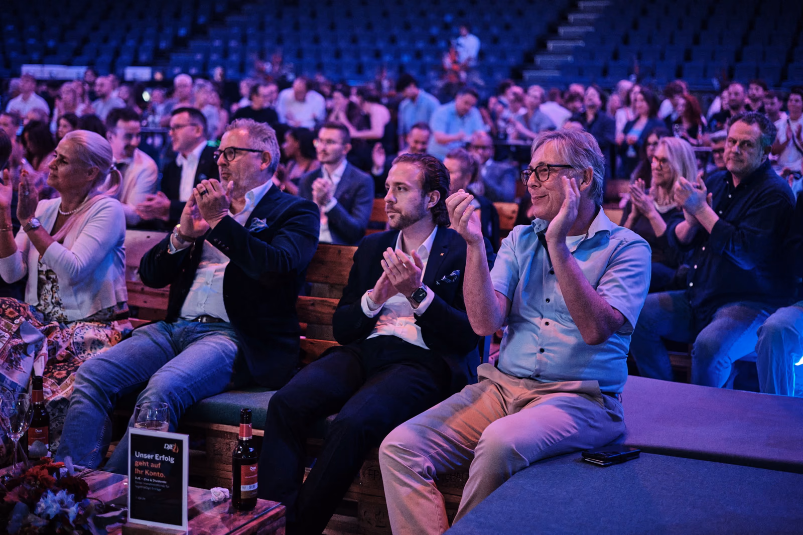 Gäste im Innenraum applaudieren einem Pitch auf der Bühne.