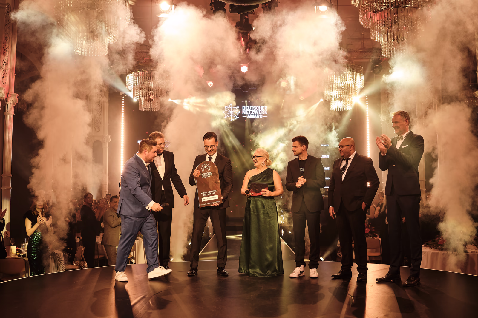 Deutscher Netzwerk Award: die Preisträgergruppe steht im Nebel und Scheinwerferlicht auf der Bühne.